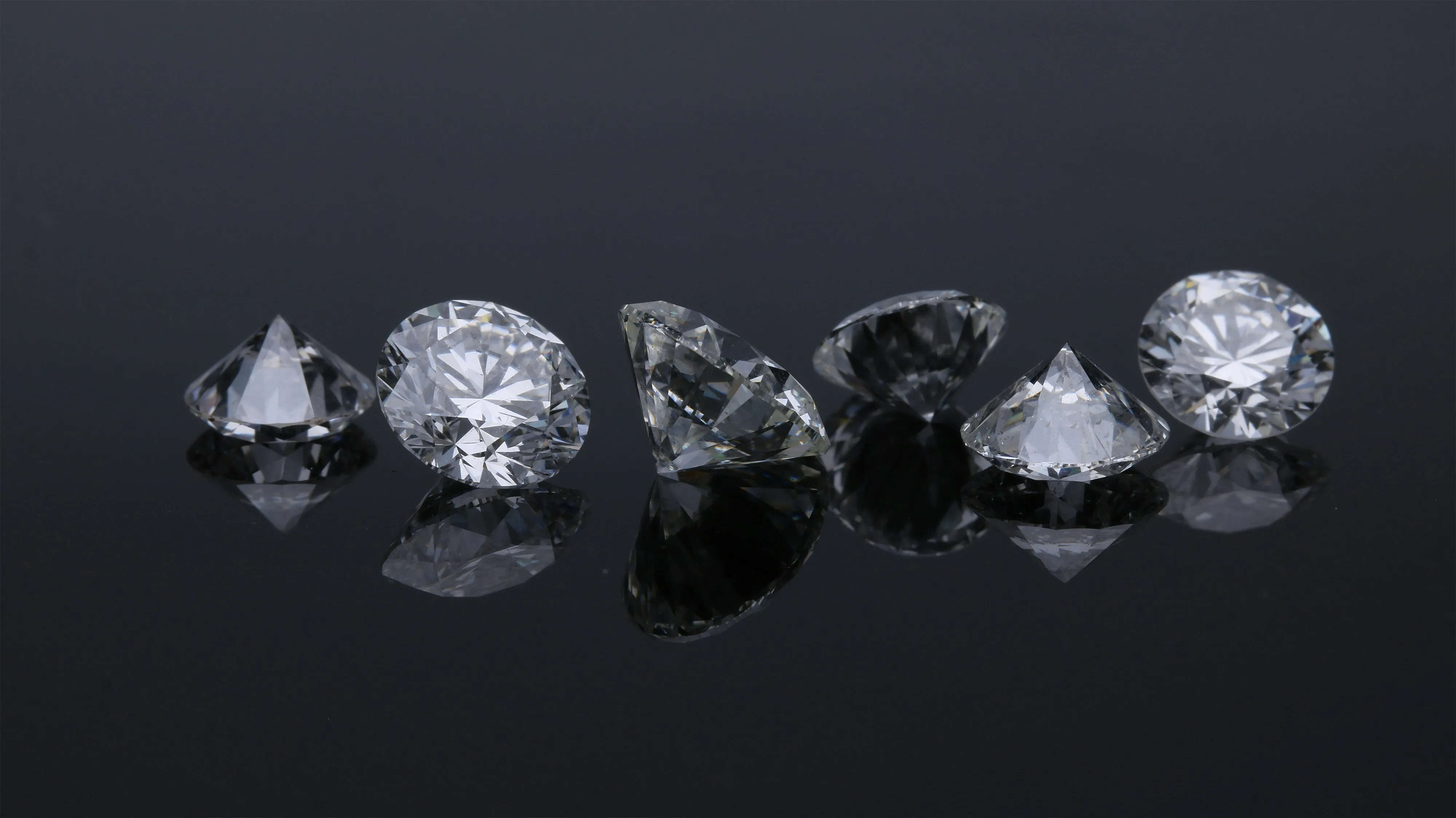 Round brilliant cut diamonds on a dark reflective surface